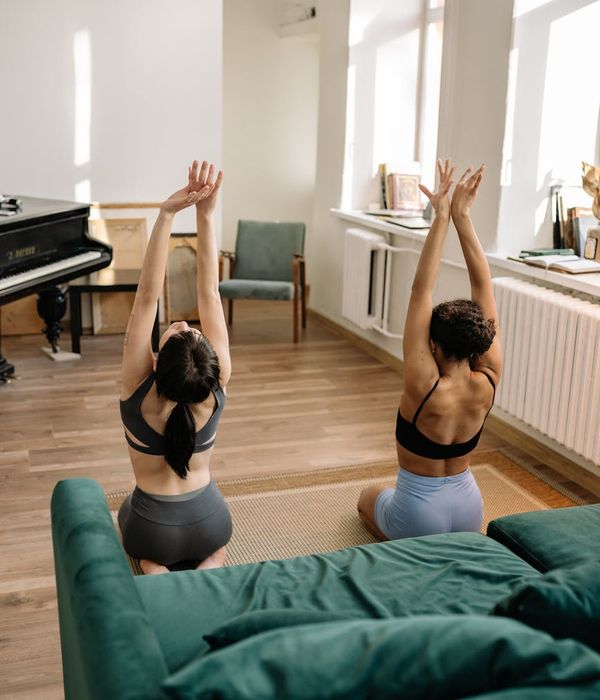 A calm person in a comfortable meditative yoga pose in a sunlit room.